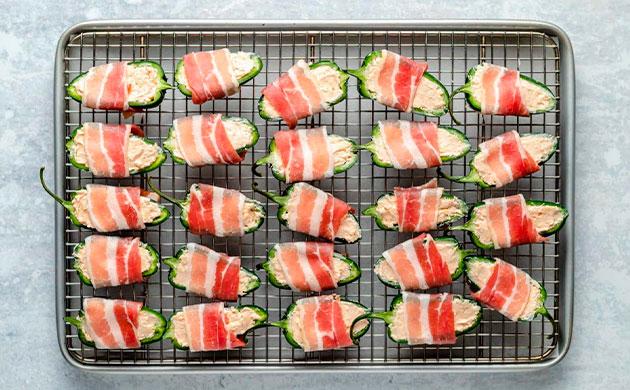 Заворачиваем халапеньо в бекон перед запеканием Оборачивание фаршированных перцев халапеньо ломтиками бекона